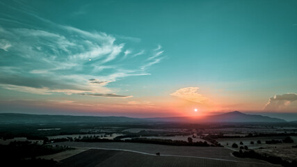 Les teintes magenta et dorées du coucher de soleil embrasent le ciel et le champ, créant une...