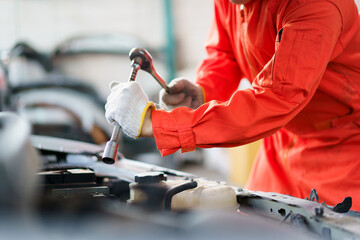 Automobile technician working in auto garage, technician holding a wrench preparing to repair...