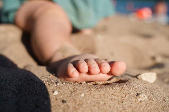 Cute foot with the fingers of a small child on the sand on the beach