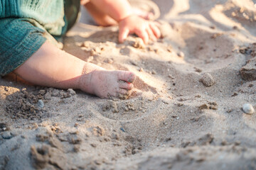 Cute foot with the fingers of a small child on the sand on the beach
