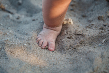 Cute foot with the fingers of a small child on the sand on the beach