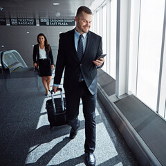 Business man, smartphone and suitcase in airport hallway with smile, thinking or idea for...