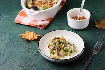 Green bean casserole with creamy sauce topped with crispy fried onions in a white ceramic plate on...