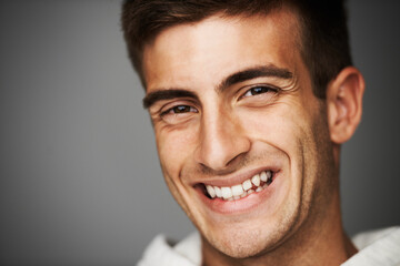 Portrait, smile of man and student in studio isolated on a gray background mockup space. Face, happy young person and model with positive facial expression, excited and cheerful in Spain at college