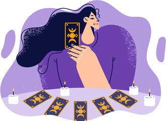 Woman predictor or fortune teller with tarot cards laid out on table with candles predicts future.