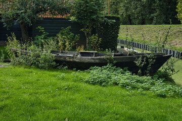 an old rowing boat that seems to be wrecked on the shore. Weeds grow through the holes in the boat