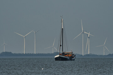 Large old sailing boat on the IJsselmeer with windmills in the background