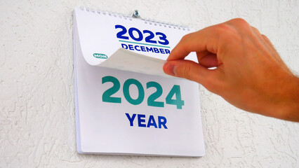 Close-up of a male hand flipping through the December page of 2023 wall calendar followed by the...