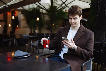 Young adult student using smart phone while at caffe going to school campus. Connected with friends everywhere, checking online bank, posting stories.