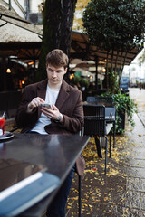Young adult student using smart phone while at caffe going to school campus. Connected with friends everywhere, checking online bank, posting stories.