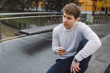 Fototapeta premium Young adult student using smart phone while going to school campus. Connected with friends everywhere, checking online bank, posting stories.