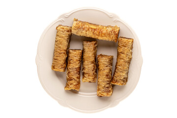 Several pieces of sweet baklava on a white ceramic dish on a white background, macro, top view.