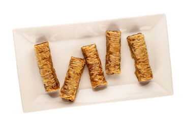 Several pieces of sweet baklava on a white ceramic dish, macro, top view.