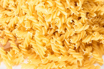 Uncooked Fusilli Pasta Scattered on Wooden Board and White Table. Raw and Dry Macaroni. Fat and...