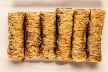 Several pieces of sweet baklava on a white ceramic dish, macro, top view.