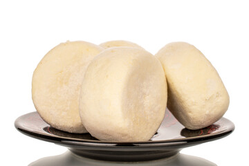 Several frozen semi-finished cheesecakes on a ceramic saucer, macro, isolated on white background.