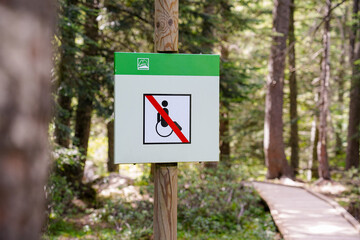 disability sign with a crossed out wheelchair in the forest. Universal accessibility conceptual...