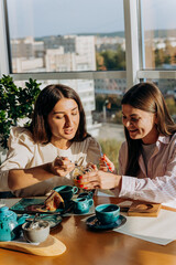Smiling female friends drinks coffee and eating dessert in restaurant during lunch time