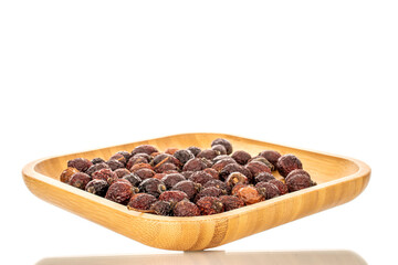 Several dry rosehip berries on a bamboo tray, macro, isolated on white background.