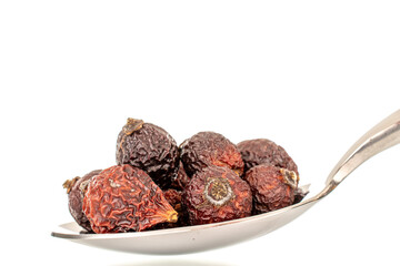 A few dry rose hips with a metal spoon, macro, isolated on a white background.