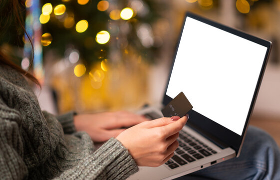 Christmas online shopping, sales and discounts promotions during winter holidays, online shopping at home. Mock-up. Feamale hands on the laptop with credit card and blurred bokeh lights
