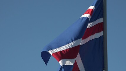 Icelandic flag flutters in the wind. Iceland national flag of european country. Cloudy sky background.