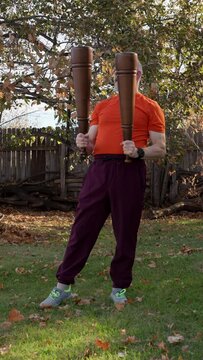 senior, athletic man is exercising with heavy wooden Persian meels in a backyard