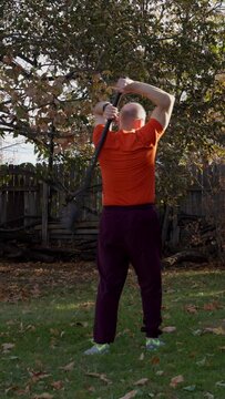 senior, athletic man is exercising with a steel mace performing 360 movement, backyard fall scenery