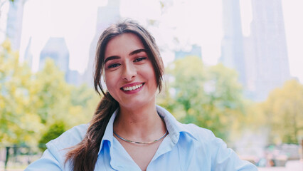 Portrait of joyful beautiful Caucasian woman outdoors, smiling at camera during walk in park. A...