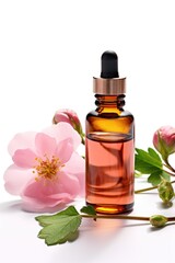 A bottle of essential oil next to a pink flower. Dark glass bottle on white background.