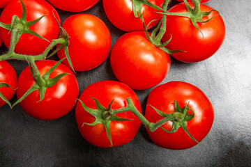 Above view studio shot of fresh tomatoes on black cutting board.