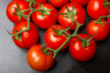 Above view studio shot of fresh tomatoes on black cutting board.