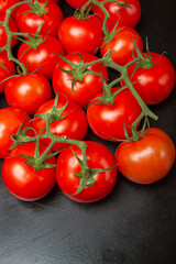 Above view studio shot of fresh tomatoes on black cutting board.