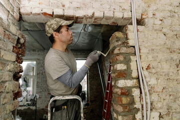 A young man places bricks in a doorway.