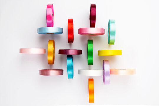 Set of many colorful satin ribbon spools on white background. Textile ribbon reels