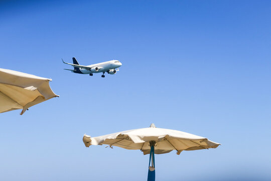 the plane lands over the sea, the beach. The plane flies over the beach umbrellas