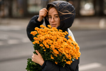 Bouquet of yellow flowers in the hands of a young girl wearing glasses