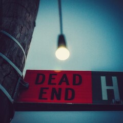 Dead End sign with a blurred illuminated light bulb in the background