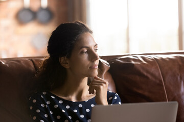 Fototapeta na wymiar Close up thoughtful woman distracted from laptop, sitting on couch, looking to aside and touching chin, pensive young female feeling unmotivated, freelancer working on online project at home