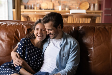 Close up overjoyed millennial couple hugging, relaxing on cozy couch together, happy woman and man...