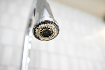 The chrome faucet is covered with lime scale.