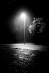 Vertical shot of heavy rain illuminated by street light pouring in the street at night