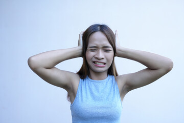 Asian woman covers her ears with her hands to prevent hearing