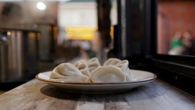 Khinkali are standing on the street, cooling down. Georgian cuisine, khinkali on a plate, on the street in the evening.
