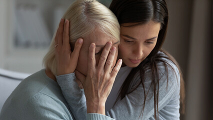Caring daughter embracing, comforting soothing unhappy crying mature mother close up, helping to overcome problems, loving granddaughter cuddling supporting stressed older grandmother - obrazy, fototapety, plakaty