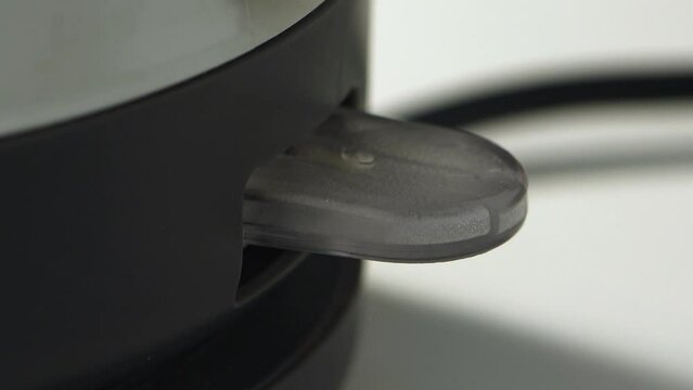Extreme close-up boiling electric kettle&rsquo;s purplish illuminated power light turned on then turns off automatically  
