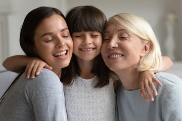 Head shot portrait three generations of women hugging, smiling mature grandmother, young mother and...