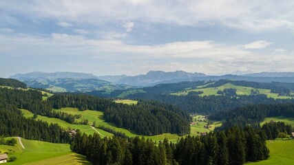 Fototapeta na wymiar Aerial view of lush green valleys and trees near mountains in Emmental, Switzerland