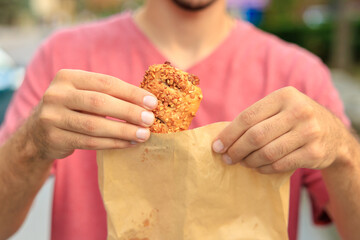 A guy's hand holds sweet pastry with jam, snack and fast food concept. Selective focus on hands with blurred background