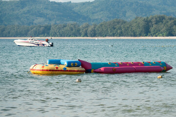 Different colorful inflatable boats for playful beach sport in water by blue sea, anchored at...